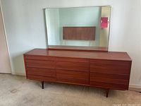 Front view of teak dresser with attached mirror reflecting room