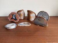 Full view of all six geodes arranged on wood surface, showing size, shape, and interior colors