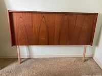 Front view of wooden headboard with visible wood grain and support legs.