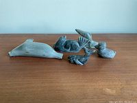 Front view of five carved stone bird sculptures arranged on wooden surface, showing different sizes and colors from light to dark gray.