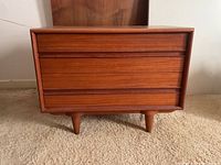 Front view of wooden side table showing three drawers and tapered legs.