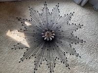 Overall view of round metal sunburst sculpture laid flat on carpet