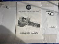 Image of the instruction manual for the Simply Ming Automatic Electric Spiralizer, lying on top of the original box packaging with MaxSold auction label attached.