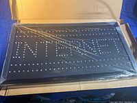LED sign unlit, showing LED bulbs arranged in the word 'INTERNET' inside a black rectangular board, partially covered in plastic wrap and sitting inside a cardboard box.