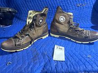 Pair of brown leather and canvas Converse Chuck Taylor All Star men's size 12 high-top sneakers photographed from the outside of the shoes showing the Converse star ankle patch.