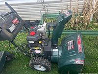 Side view showing full machine: auger housing, engine, wheels and handles