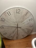 Front view of Thomas Kent round wall clock with wooden texture and printed numbers