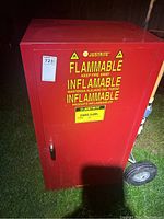 Front view of red Justrite flammable storage cabinet with warning labels