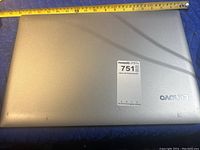 Top view closed silver Lenovo laptop with measuring tape showing approximate width.