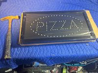LED pizza sign in original box, unlit, showing clear LED arrangement under plastic covering next to hammer for scale.