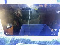 Front view of LG microwave showing reflective black glass door and digital display at upper right.