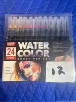 Front view of unopened 24-piece watercolor brush pen set with branding, item count, and product features.
