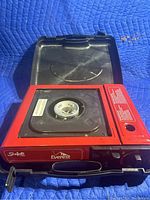 Open stove showing red body and single burner with control knob; stove shows light use with some marks but no major damage.