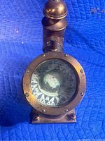 Front view of vintage brass nautical ship's compass with visible compass card.