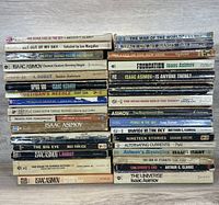 Stack of vintage sci-fi paperback books showing titles and authors on spines, mostly by Isaac Asimov and Arthur C. Clarke.