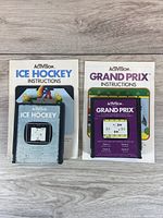 Photo of Activision Ice Hockey and Grand Prix game cartridges with instruction manuals showing cartridge labels and artwork.