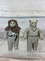 Front view of two 1983 Kenner Star Wars Ewok figures, one with and one without brown hood