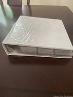 White three-ring binder with plastic protective cover, edges slightly worn, filled with baseball cards