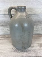 Front view of 12 inch salt glazed stoneware jug with handle on wooden background.