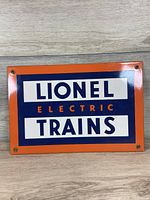 Front view of the metal sign showing Lionel Electric Trains branding with orange, blue and white colors, 12x8 inch size.