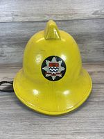 Front view of yellow firefighter helmet showing overall shape and the crest emblem on front.