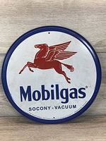 Front side of round Mobilgas metal sign showing the red Pegasus logo and Mobilgas text with Socony-Vacuum branding.