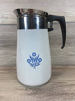 Front view of the vintage Corningware coffee carafe showing the Blue Cornflower floral design and black handle.