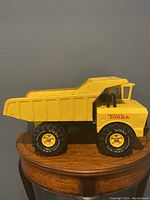 Side view of the vintage Tonka metal dump truck showing its yellow body, black and yellow wheels, and overall condition.