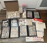 Overview showing six blue binders, cardboard box of loose stamps, and Canada souvenir cards