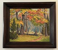 Frontal photo of the framed oil painting showing the autumn wooded landscape and dark wood frame