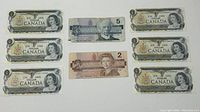 Six 1973 $1 Canadian banknotes, one 1986 $2 banknote, and one 1986 $5 banknote arranged flat.