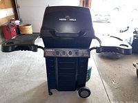 Front view of Fiesta 345 BBQ grill with side shelves extended, showing control panel and wheels.