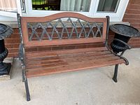 Full view of wood and metal outdoor bench showing whole seating area and backrest with decorative metal design.