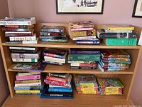 Wide view of wooden bookshelf densely packed with various books, including stacks of many genres and formats.