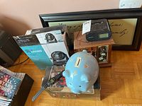 Photo showing original boxed 8 inch Turbo Fan, Sony alarm clock on wooden jewelry box, blue piggy bank, and framed sign art in background