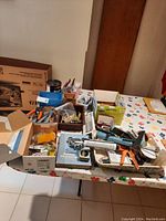 Overview of assorted tools, paints, gloves, reference book on a table