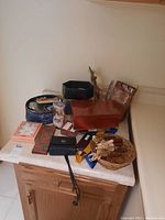 Overview of the assorted home decor items on a marble-topped cabinet including boxes, frames, and baskets.
