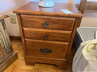 Front view of wooden two-drawer nightstand showing drawers and handles.