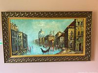Framed oil painting of Venetian canal with gondolas, buildings, and blue sky, shown wall mounted.