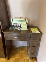 Front view of the sewing desk with Singer Stylist 513 sewing machine on top along with manual booklet.