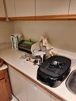 Countertop view showing Hamilton Beach electric grill, meat slicer, and FoodSaver sealer in original box.