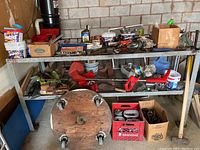 Full view of metal workbench with various tools and hardware arranged on shelves and surface.
