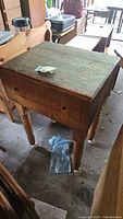Full view of the vintage wooden butcher's block showing the thick, well-worn top surface and the four legs with casters attached.
