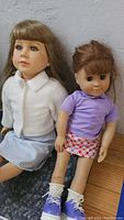 Both dolls sitting side by side against a gray background showing overall condition and appearance