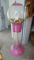 Full view of pink gumball machine showing base, globe, lid and loaded gumballs
