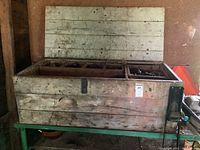 Wooden trunk with compartments and hinged lid on green metal stand