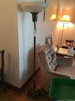 Full view of the vintage floor lamp standing next to a chair and wall, showing the base and lamp shade.