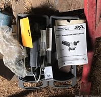 Photo showing Skil Model 9405 angle grinder/sander placed inside a black plastic carrying case with user manual and some additional small accessories.