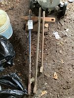 Overview of three metal pry bars placed on the ground, showing wear and one with blue paint residue.