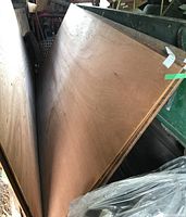 Five sheets of 1/4 inch mahogany plywood leaning upright, showing flat surface over side edge and thickness.